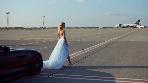 乌克兰基辅- 2017年9月2日：一位优雅的金发美女在机场靠近奔驰Amg Gt 50版跑车的地方摆姿势。 为庆祝50周年而设计的新型2017年超级跑车 — 图库照片