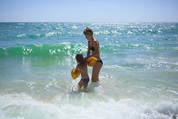 Deniz kıyısındaki kumsalda oynayan ve zıplayan altı yıllık mutlu bir aile. — Stok fotoğraf