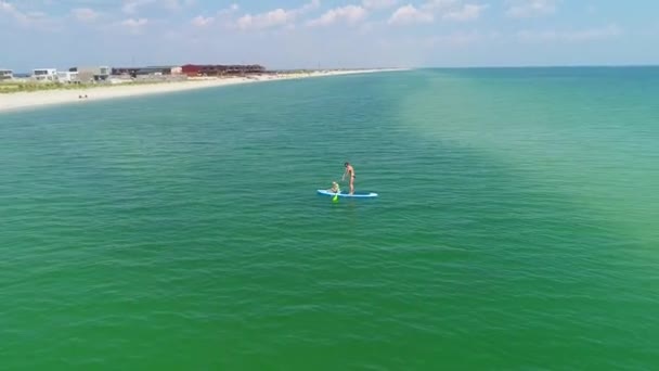 Little girl in a life vest sitting on the paddle board with mother. — Stock Video