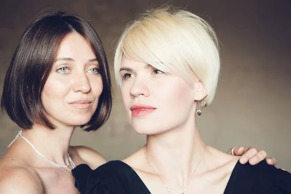 Портрет двух привлекательных кавказских улыбающихся женщин блондинка и брюнетка студии выстрелил короткие волосы глядя в камеру . — стоковое фото