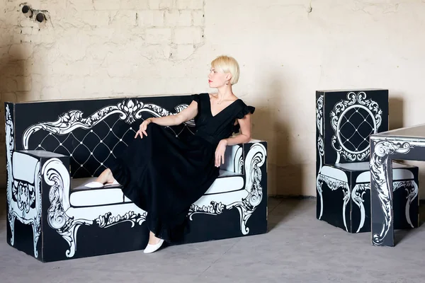 Portrét elegantně krásné mladé ženy pózující na lepenkovém starožitném gauči. — Stock fotografie