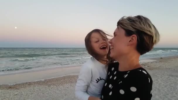 아이 주위를 돌고 있습니다. 바다를 배경으로 행복 한 가족. 엄마와 딸 이 해변에서 즐거운 시간을 보내는 모습 — 비디오