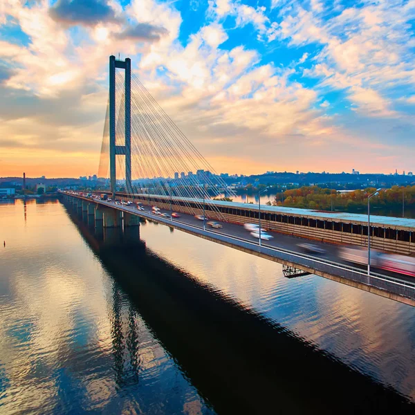 Automobile et pont ferroviaire à Kiev, la capitale de l'Ukraine. Pont au coucher du soleil sur la rivière Dniepr. Pont de Kiev dans le contexte d'un beau coucher de soleil à Kiev. Pont sous le soleil du soir — Photo