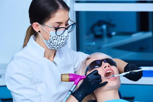 Retrato de una dentista y una joven en un consultorio — Foto de Stock