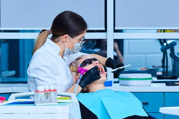 Dentista feminina examinando um paciente no consultório odontológico para uma mulher . — Fotografia de Stock