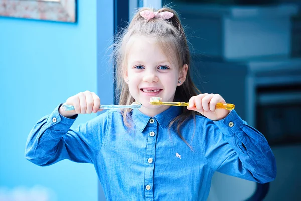 Une petite fille mignonne se brosse les dents avec deux brosses à dents . — Photo