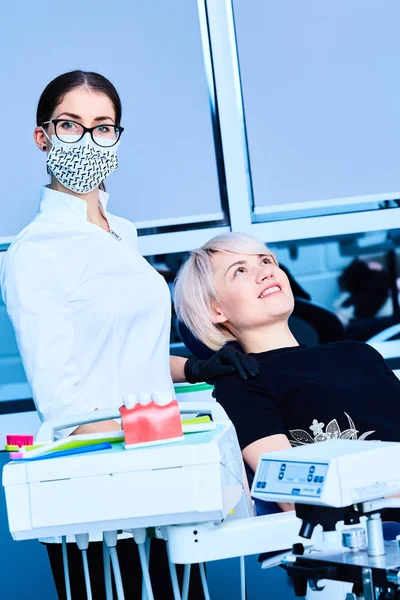 Dentista feminina examinando uma paciente feminina na clínica — Fotografia de Stock