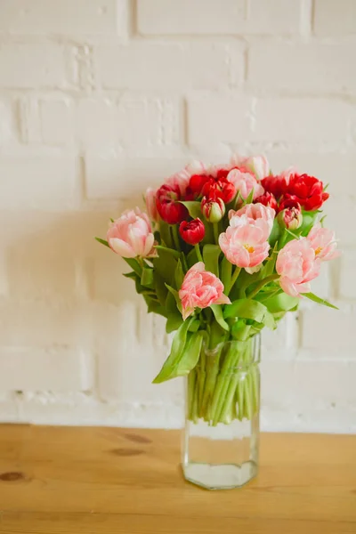 Glazen vaas met boeket van mooie tulpen op bakstenen muurachtergrond — Stockfoto