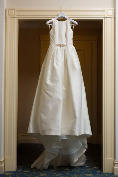 Wedding dress hanging up by the door. — Stock Photo, Image