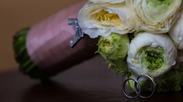 Strauß weißer Rosen und silberne Trauringe. — Stockfoto