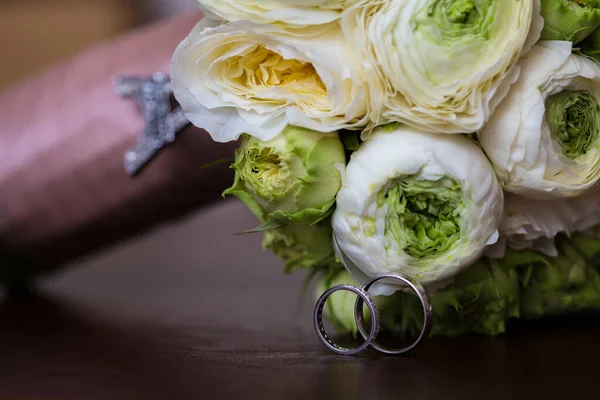 Bouquet van witte rozen en zilveren bruiloft ringen. — Stockfoto