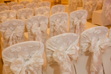 Düğün töreni. Lüks bir yere kurulmuş. Sandalyede fiyonklar.