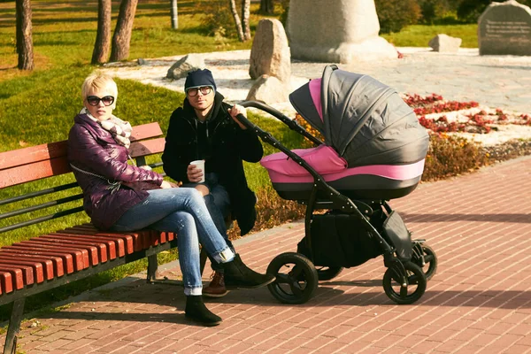 Family walk in the autumn park with a pram. Mom, dad and baby outdoors. — Stock Photo, Image