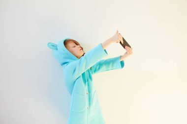 Neşeli küçük kız 7 yaşında, beyaz arka planda selfie çekiyor. Sosyal Medya Bağımlılığını Kabul Et.