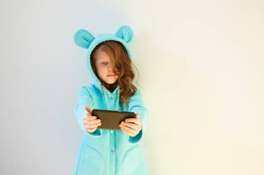 Neşeli küçük kız 7 yaşında, beyaz arka planda selfie çekiyor. Sosyal Medya Bağımlılığını Kabul Et.