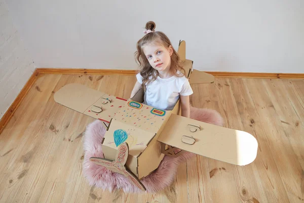 Little dreamer girl playing with a cardboard airplane. Childhood. Fantasy, imagination. — Stock Photo, Image