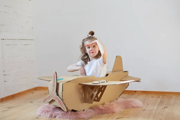 Little dreamer girl playing with a cardboard airplane. Childhood. Fantasy, imagination. — Stock Photo, Image