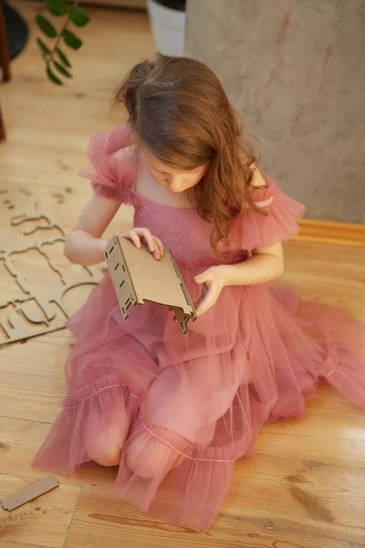 Девушка, играющая с картонной мебелью кукольного домика . — стоковое фото