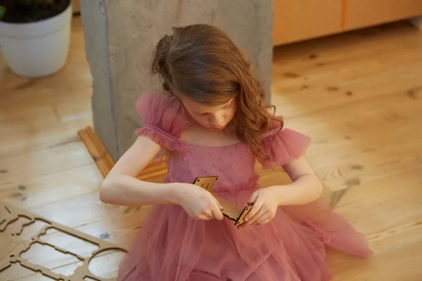 Una chica jugando con muebles de muñeco de juguete de cartón . — Foto de Stock