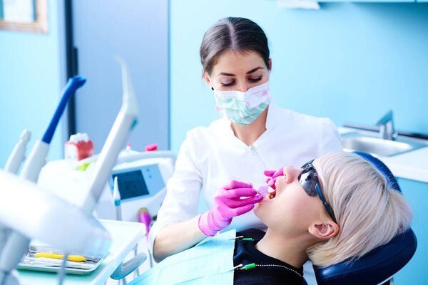 Красивая пациентка, проходящая стоматологическое лечение в кабинете стоматолога. Женщина, посещающая своего дантиста
