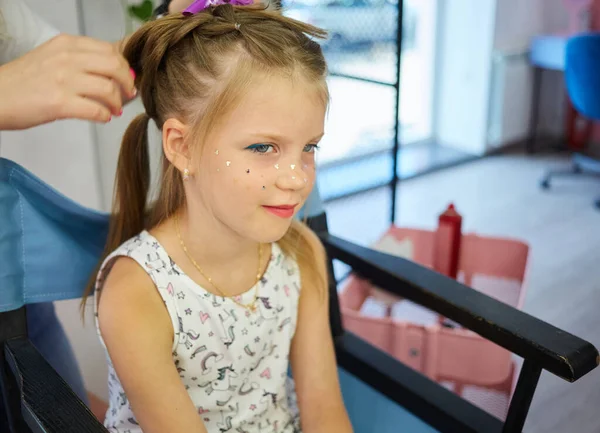 Hairdressing services. Reating hairstyle. Hair styling process. Children hairdressing salon