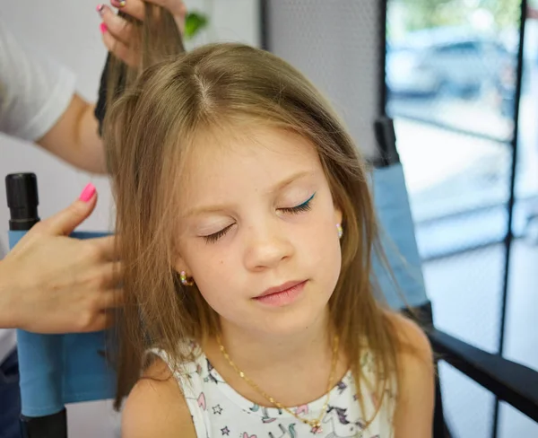 Hairdressing services. Reating hairstyle. Hair styling process. Children hairdressing salon