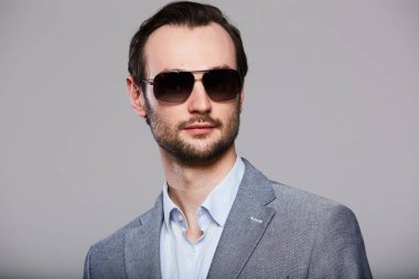 Gri ceketli yakışıklı, zarif genç adamın stüdyo portresi.