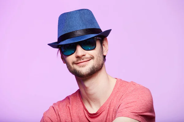Een jonge hippe man met een blauwe hoed. Studio schot over roze achtergrond. — Stockfoto