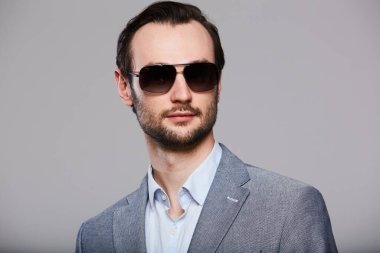 Gri ceketli yakışıklı, zarif genç adamın stüdyo portresi.