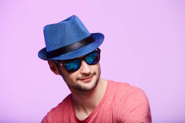 Mavi şapkalı genç hippi. Stüdyo çekimi pembe arkaplanda.