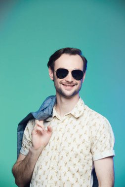 Yeşil arka planda güneş gözlüğü takan yakışıklı adamın stüdyo fotoğrafı..