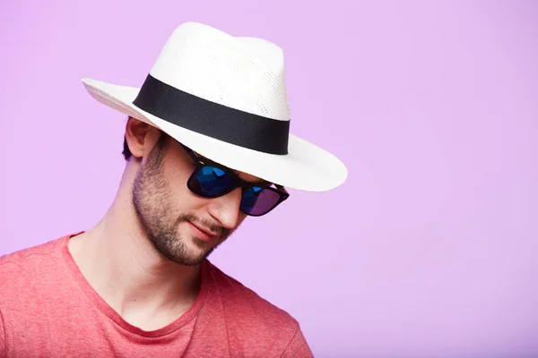 Zbliżenie portret niesamowitego hipstera noszącego kapelusz Fedora z intensywnym spojrzeniem w kamerę. Strzał w głowę na różowym tle studio. — Zdjęcie stockowe