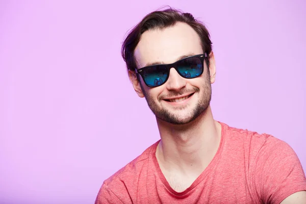 Primer plano retrato de hipster impresionante con gafas de sol con mirada intensa en la cámara. Headshot sobre fondo de estudio rosa . — Foto de Stock