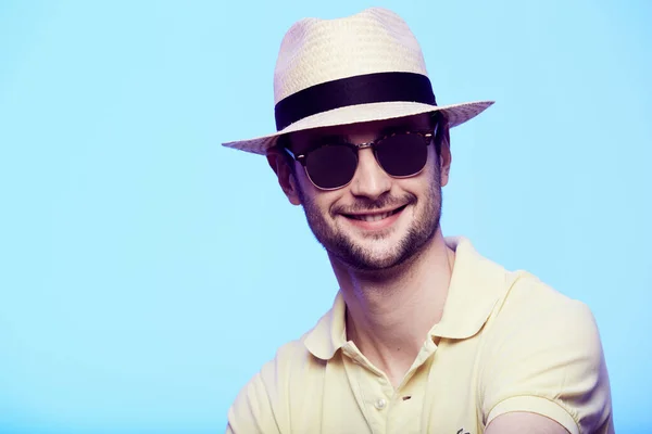 Ritratto ravvicinato di hipster impressionante che indossa cappello fedora con sguardo intenso alla fotocamera. Headshot su sfondo blu studio . — Foto Stock