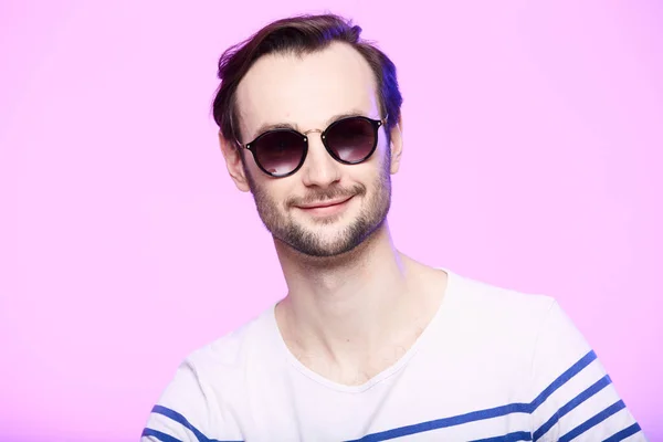 Estudio de tiro de hombre guapo con gafas de sol sobre fondo rosa . — Foto de Stock