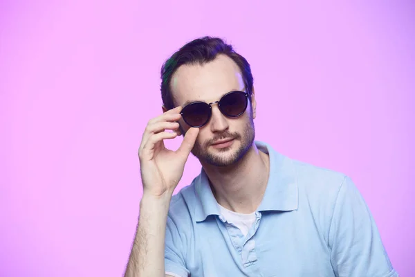 Plan studio d'un bel homme portant des lunettes de soleil sur fond rose . — Photo
