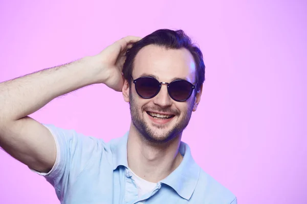 Studio shot van knappe man het dragen van een zonnebril over roze achtergrond. — Stockfoto