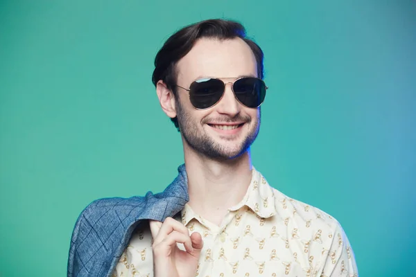 Studio shot of handsome man wearing sunglasses over green background. — Stock Photo, Image