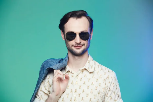 Studio shot of handsome man wearing sunglasses over green background. — Stock Photo, Image