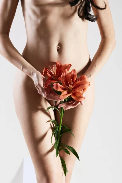 La parte íntima del cuerpo femenino con la flor en las manos. Primer plano de un cuerpo de mujer con flores en el pubis. Sin retoque . — Foto de Stock