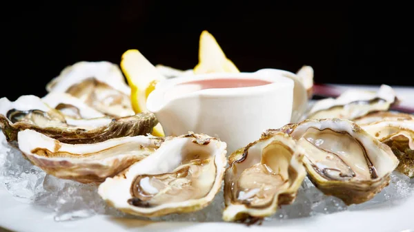 Opened fresh oysters with lemon on dish. Shallow dof — Stock Photo, Image