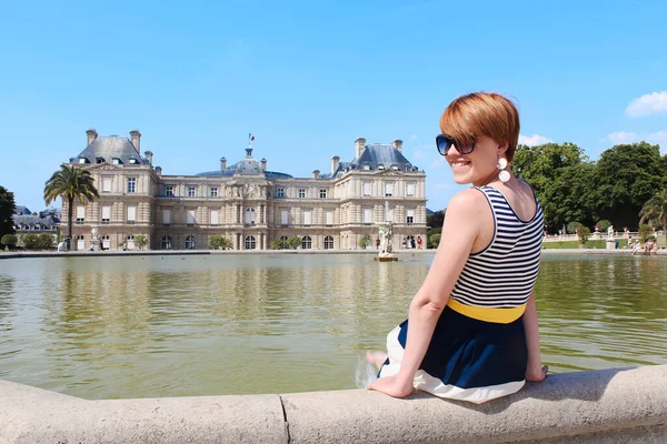 Young woman have a rest at the Luxembourg Garden with beautiful Luxembourg Palace on the background during the morning light in Paris — Stock Photo, Image