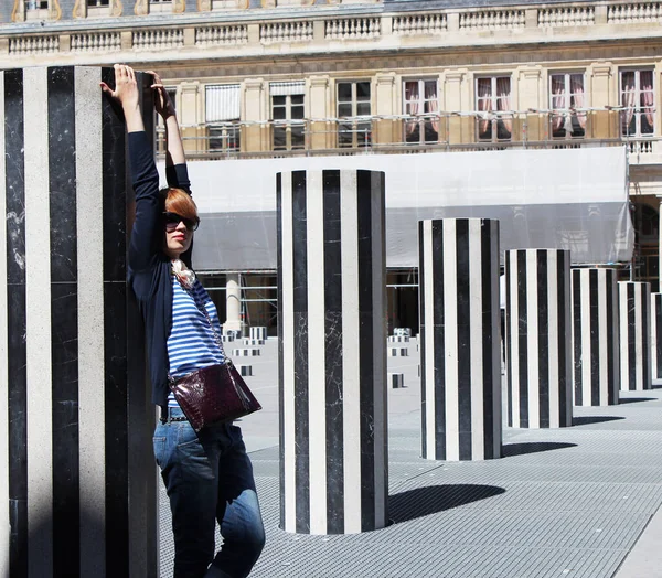 Mooie jonge vrouw poserend in de Colonnes de Buren in Palais Royale in Parijs. — Stockfoto