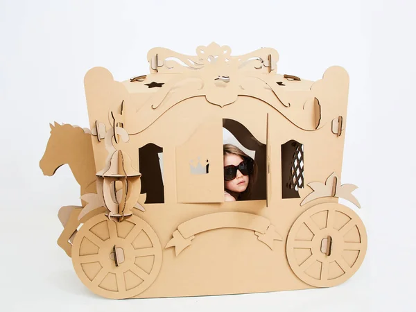 Little princess in crown 7 years old play in carriage made of brown cardboard — Stock Photo, Image