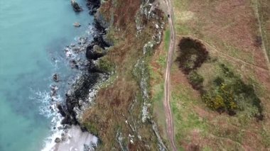 Deniz kıyısının yukarıdan aşağı görüntüsü, taşlı kayalar ve İrlanda 'da okyanus dalgalarını kıran dev uçurumlar.