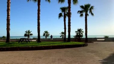 Girit 'teki otelin camlarını avuçlarının arasında güneş ışığıyla temizleyen bir kadın. Arka planda deniz var. Girit, Yunanistan.