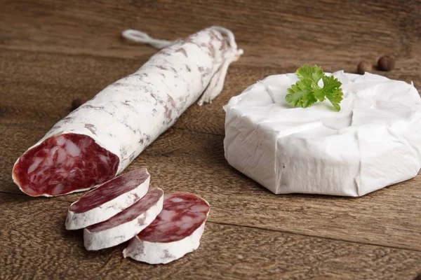 Traditional sliced salami on wooden board with brie Camembert — Stock Photo, Image