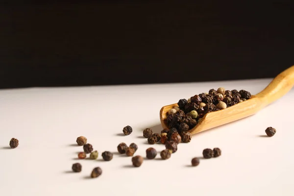 Guisantes de pimienta blanco negro rojo en una cuchara de madera — Foto de Stock