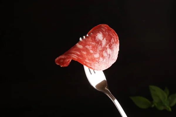 Salchicha Salchichón en un tenedor sobre un fondo negro oscuro — Foto de Stock