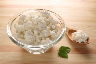 ahşap arka plan üzerinde bir cam kase süzme peynir